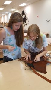 Deb Johns showing a student how to put together a leather purse